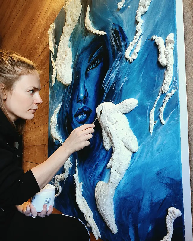 Alexandra Berthouzoz modelant la matière en relief sur une toile, dans son atelier.
